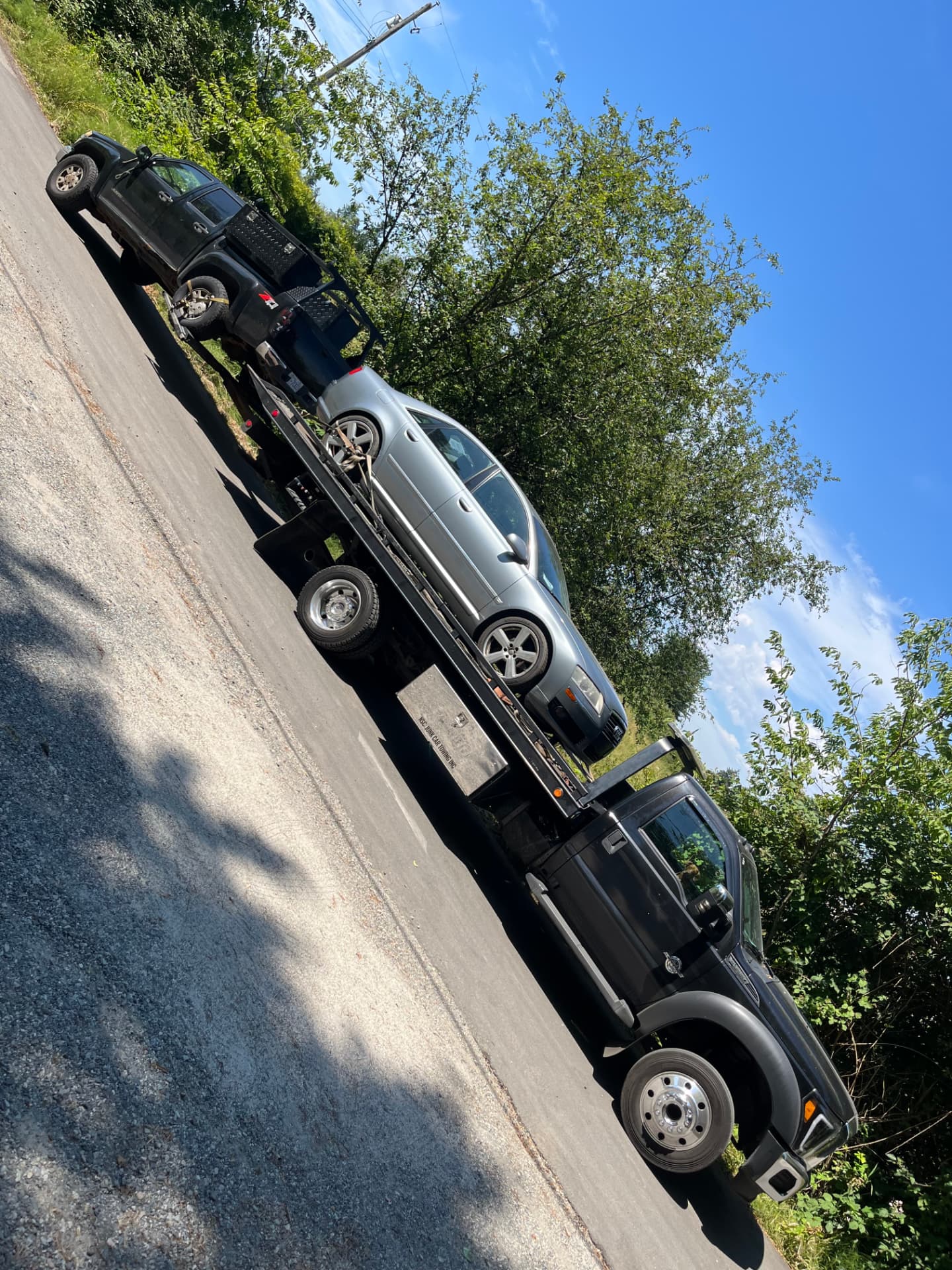 A sedan winched onto the flatbed deck of Jay's tow truck