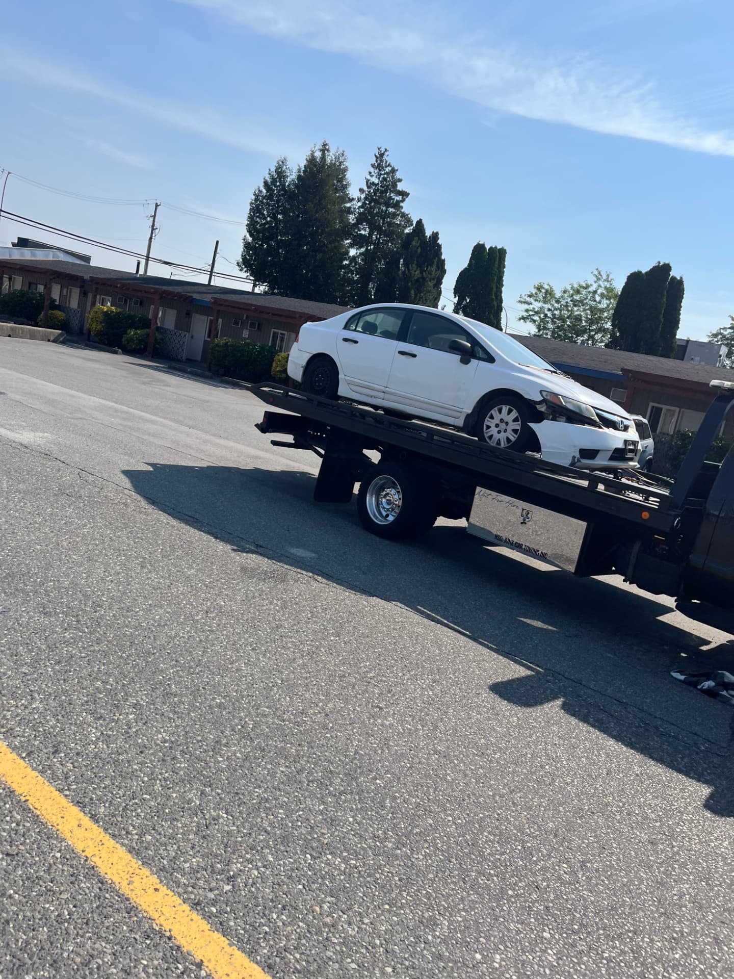 A white Honda Civic with front-end damage loaded on Jay's flatbed